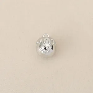 Detailed shot of a small silver metal charm pendant with intricate design for DIY jewelry.