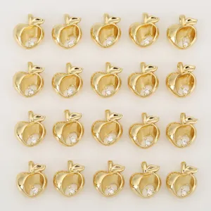 Close-up detail of small gold apple pendant with sparkling zircon inlay for DIY jewelry design.