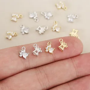 Close-up detail shot of sparkling zircon pet paw charms on fingers for DIY jewelry making.