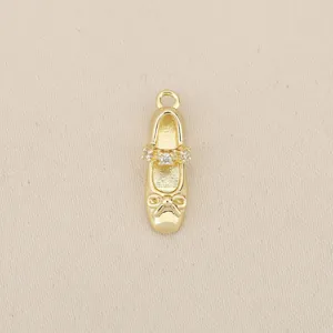 Close-up detail of a gold-plated ballet shoe pendant with sparkly zirconia and a cute bow.