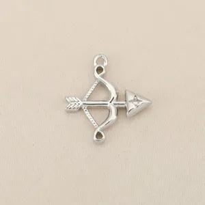 Detailed shot of bow and arrow charm pendant jewelry accessory silver tone metal.