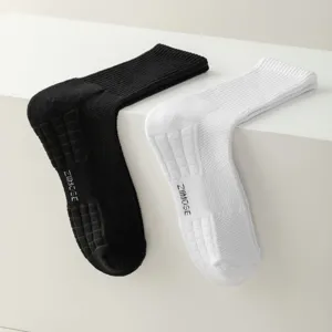 Detailed view of athletic crew socks in black and white featuring breathable knit mesh and sole grip text.