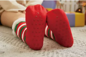Nahaufnahme von kuscheligen roten und grünen Weihnachtsplüschsocken mit Antirutsch-Noppen.