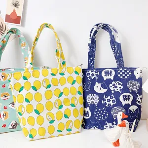 Close-up detail of cute printed canvas bento tote bags showing animal and fruit patterns.