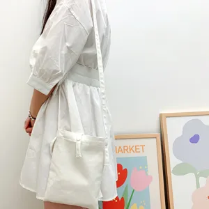 Nahaufnahme einer minimalistischen einfarbigen Canvas-Umhängetasche an Model im Alltag.