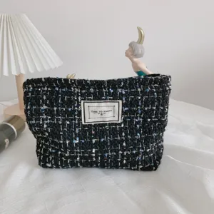 Black and blue tweed cosmetic bag with chic front label, spacious travel makeup storage pouch.