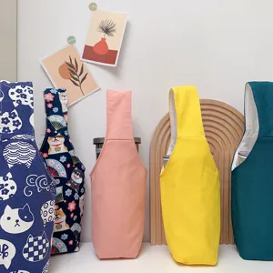 Detailaufnahme von bunten Stoff-Becherhüllen und Tragetaschen mit niedlichen Mustern.