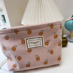 Gros plan détaillé de la trousse de toilette rose en velours côtelé avec motif ananas.