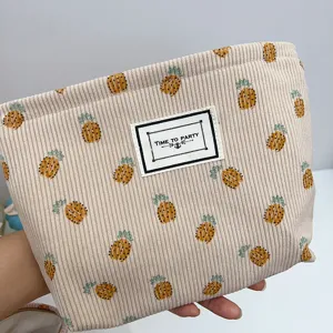Détail de trousse de maquillage de voyage en velours côtelé avec joli motif ananas et zip.