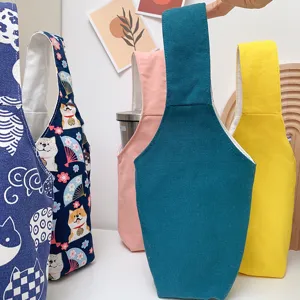 Bunte Stoffbecherhülle und Milchtee-Tragetasche im Detail, mit süßen Cartoon-Mustern.