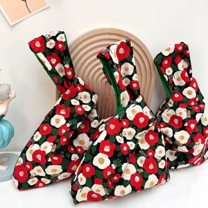 Japanese style knot wrist bag detail showing red camellia floral and cute cat print pattern.
