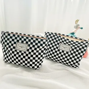 Black and white checkered cosmetic bag detail view, canvas storage pouch with fabric label.