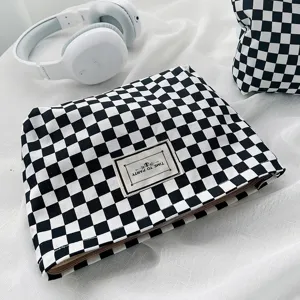 Detailed shot of black white checkerboard canvas cosmetic bag with zipper and sewn label.