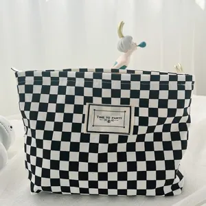 Black and white checkerboard canvas cosmetic bag, stylish square makeup storage pouch detail.
