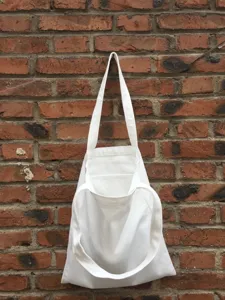 Detailansicht einer schlichten weißen Segeltuchtasche an einer rustikalen Ziegelwand für DIY.
