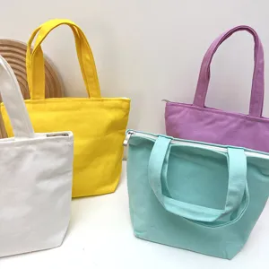 Detailaufnahme mehrfarbiger Canvas-Tragetaschen mit Reißverschluss und stabilen Doppelgriffen.
