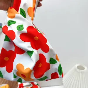 Close-up of Japanese knot wrist bag featuring vibrant red floral print and soft fabric.