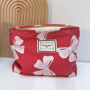 Nahaufnahme der roten Kosmetiktasche mit weißem Schleifendruck und stabilem Reißverschluss.