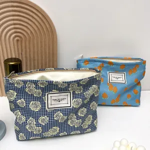 Close-up detail of fabric cosmetic pouch with floral print, zipper closure and cute label.