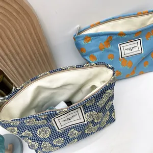 Canvas cosmetic bag detail showing cute orange and houndstooth floral prints with zipper.