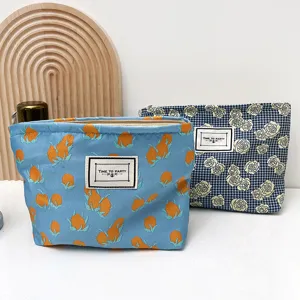Detail shot of fabric cosmetic zip pouch with floral pattern and stitched label tag interior.
