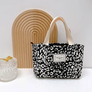 Elegante bolsa tote con estampado de leopardo blanco y negro, asas fuertes y cierre de cremallera.