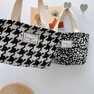 Primer plano detallado del bolso de lona con estampado clásico de pata de gallo y leopardo chic.