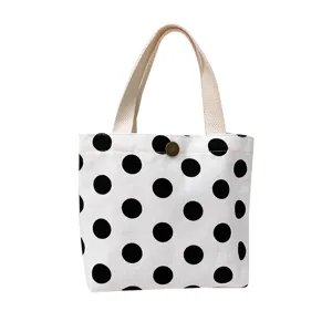 Cute black and white polka dot canvas tote bag with snap button and sturdy handles for daily use.