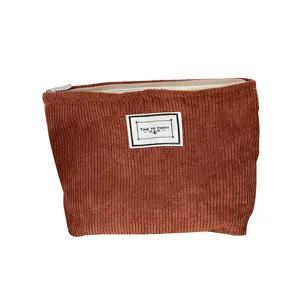 Brown corduroy makeup bag minimalist travel portable zipper pouch with decorative label.