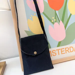 Detailansicht einer schwarzen Segeltuch Umhängetasche vor einem bunten Tulpenposter.