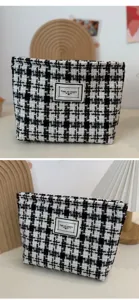 Close-up of black and white houndstooth cosmetic bag showing textured tweed fabric details.