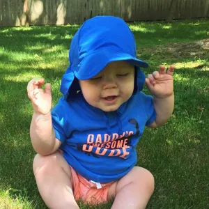 Baby zonnehoed met brede rand en nekflap gedragen buiten op het gras in de zomer.