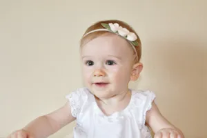 Detailed shot of baby floral headband, cute white flower hair accessory for infants.