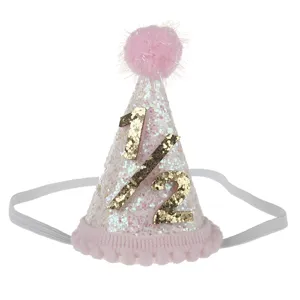 Primo piano di un cappello di compleanno rosa glitterato con numero dorato e fascia elastica.