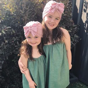 Detailed view of the cute pink baby turban hat featuring soft knit fabric and stylish multi-layered bow.