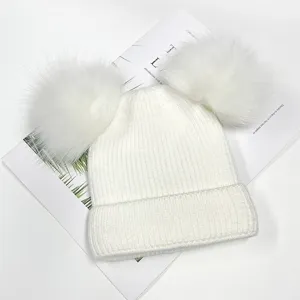 Close-up detail of white double pom-pom knit beanie, fluffy fur balls and warm fleece lining.