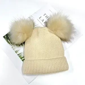 Detailed view of beige knitted winter hat with double pom-poms, warm beanie for women and kids.
