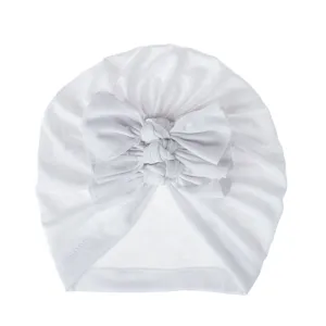 Detail shot of soft white baby turban hat with cute triple knot bow design for infants.
