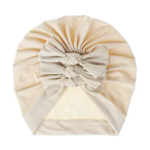 Close up of baby bow turban hat, soft knitted pleated infant headwear in beige color.