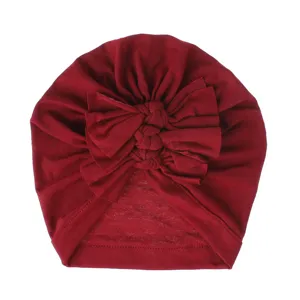 Red baby turban hat with cute knotted bow, soft knitted fabric infant headwear detail view.