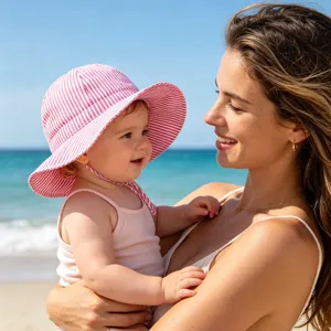 Detailed view of the cute pink and white striped baby sun hat worn outdoors at the beach.
