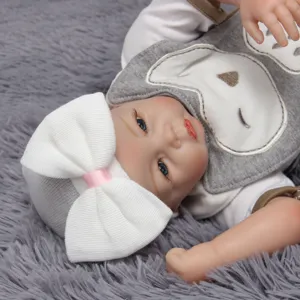 Primer plano detallado del lindo gorro de punto para recién nacido con un gran lazo blanco.