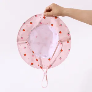 Detailed view of baby pink strawberry bucket hat lining, 100% cotton material and label.