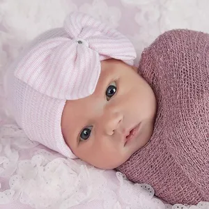 Primer plano del gorro de punto rosa a rayas para recién nacido con gran lazo y detalle.