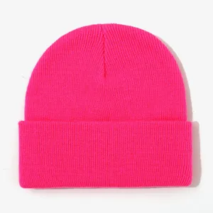 Bright pink knitted beanie close-up, warm winter cuffed hat detail view, soft cozy fabric.