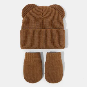 Detailansicht von braunen Baby-Strickmütze und Handschuhen mit süßen Bärenohren.