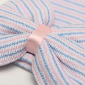 Primer plano detallado del gorro de punto para recién nacido a rayas rosas y azules con lazo.