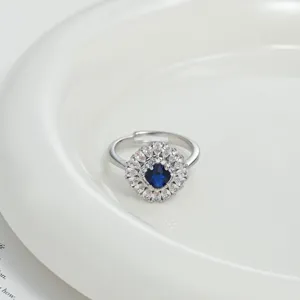 Detailed close-up of a silver open ring with blue center stone and clear zirconia halo.