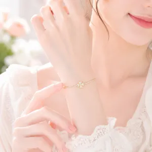 Close-up detail of a dainty four-leaf clover bracelet featuring paved zircons on a fine gold chain.