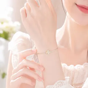 Close-up detail of a delicate micro-set zircon four-leaf clover gold-tone bracelet.